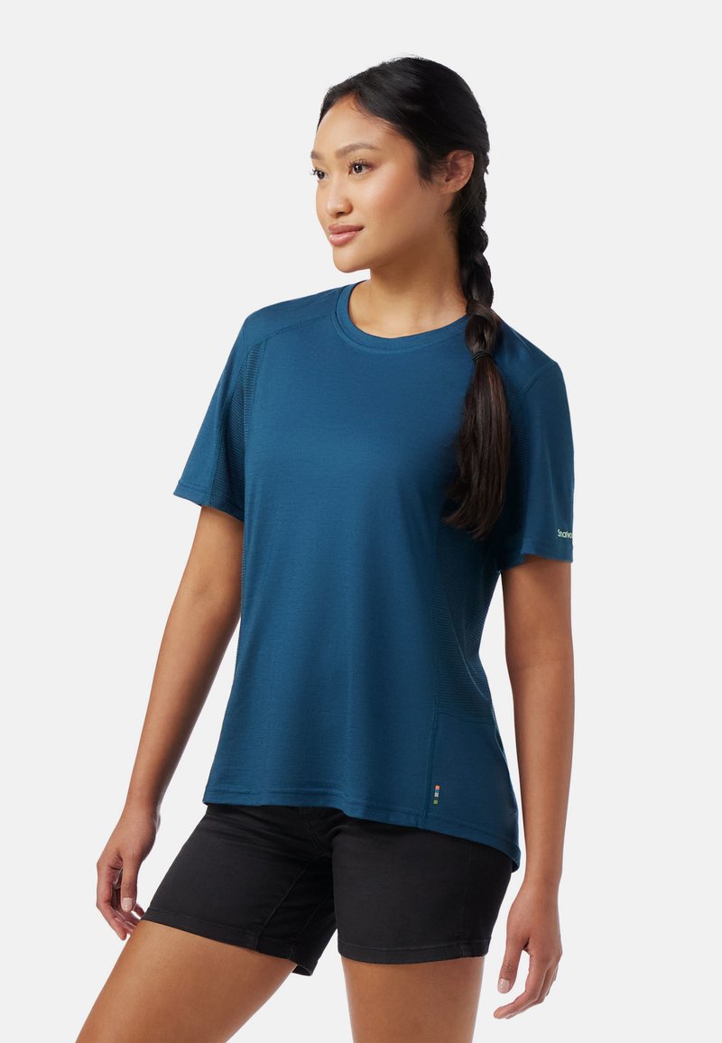 Blå kortærmet t-shirt lavet af et glat, let stof. Har en rund halsudskæring, mesh-detaljer og en subtil syning.