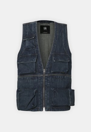 Gilet en jean avec plusieurs poches avant, un zip et un design en V. Couleur bleu foncé avec une légère texture.