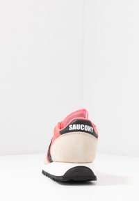 Rosa und beige Sneaker mit einem Wildlederabsatz, schwarzen Akzenten und einer strukturierten Sohle. Mit Logo auf der Rückseite und gestickten Details.