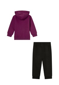 Felpa con cappuccio viola con tasca a marsupio, abbinata a pantaloni della tuta neri alla caviglia con vita elastica.