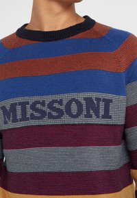 Gebreide trui met gedurfde horizontale strepen in blauw, rood, grijs en paars. Voorzien van het "MISSONI"-logo in donkere brei op borsthoogte.