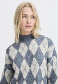 Maglione in maglia con motivo argyle grigio e crema, con collo alto e texture morbida. Vestibilità casual con spalle scese.