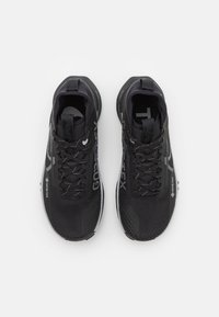 Zwarte sportschoenen met een ademend mesh bovenwerk, textuur overlays en reflecterende accenten. Inclusief veters en een gevoerde zool.