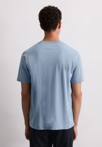  Lichtblauwe t-shirt met korte mouwen, een ronde hals en een rechte zoom. Gladde katoenen stof met een minimalistisch ontwerp en geen zichtbare versieringen.