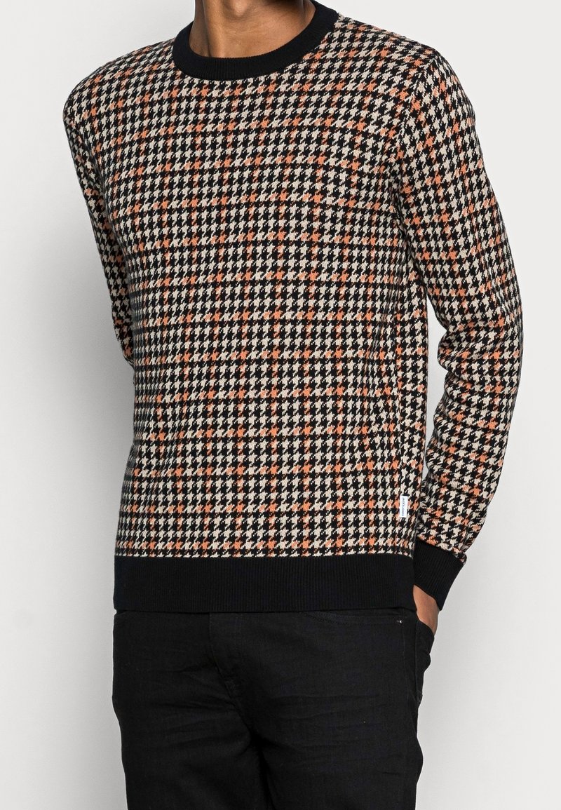 Maglione con motivo houndstooth in bianco, nero e arancione, con polsini e orlo a costine, caratterizzato da un collo rotondo e un tessuto morbido e texturizzato.