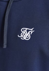 Navy blue hoodie featuring a white embroidered logo. The material is soft cotton, detailed with a drawstring and ribbed hem.
