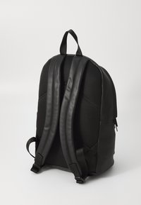Zaino nero con dorso in rete strutturata e spallacci in pelle liscia, dotato di un manico superiore e spallacci regolabili.