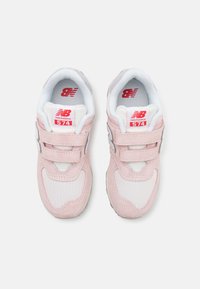 Baskets New Balance 574 roses avec tige en daim et mesh, comportant des accents blancs, deux sangles Velcro et un logo sur la languette.