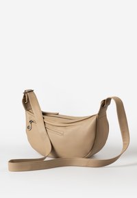 Beige leather shoulder bag with a sleek, curved design, adjustable strap, zip closure, and exterior pocket. Smooth texture and minimalist style.