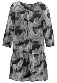 Robe à motifs noir et blanc, coupe ample, encolure ronde, détail noué à l'avant, manches trois-quarts et ourlet à volants superposés.