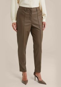 Bruine faux leren broek met een slim fit. Bevat voornaad, zijzakken en een zachte textuur. Gepaard met beige hoge hakken.