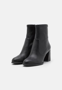 Black leather ankle boots with a smooth texture, rounded toe, and a mid-height block heel. Features zip closure and minimal stitching.