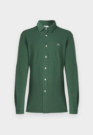 Groene polo met lange mouwen, gemaakt van katoen, met een klassieke kraag, een knoopsluiting aan de voorkant en een klein geborduurd logo op de borst.