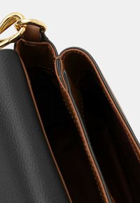 Borsa a mano in pelle nera con interno marrone. Presenta una chiusura in metallo dorato, un design elegante e bordi finemente cuciti. Due scomparti visibili.