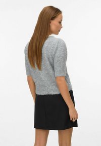 Gray fuzzy sweater with short sleeves, round neck, and cropped design, paired with a black skirt. Soft texture and casual silhouette.