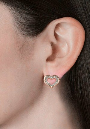 Orecchini a forma di cuore in rosé dorato, contornati da strass trasparenti e con un centro intagliato. La finitura metallica liscia conferisce un aspetto lucido.