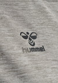 Fekete stilizált méh logó, rajta a "hummel" felirattal, világosszürke texturált anyagra nyomva.