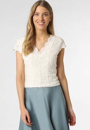 White, lace top with short scalloped sleeves and a V-neck, paired with a flowing light blue satin skirt. Textured floral pattern throughout.