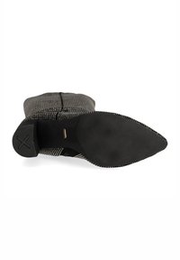 Botte de cheville à motifs noir et blanc avec un bout pointu et un tissu texturé. Elle dispose d'une semelle noire lisse avec des détails de logo subtils.