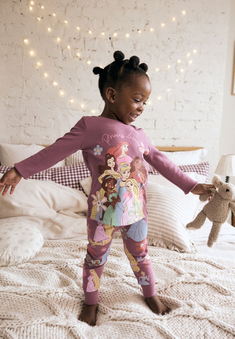 Ensemble de pyjama rose comprenant un haut à manches longues et des leggings, orné de princesses dessinées, de fleurs et du slogan « Rêves de princesse ». Tissu doux.