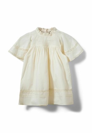 Detské šaty krémovej farby s čipkovanou ozdobou, záhybmi na živôtiku, krátkymi nafúknutými rukávmi a nariasenou sukňou na bielom pozadí.