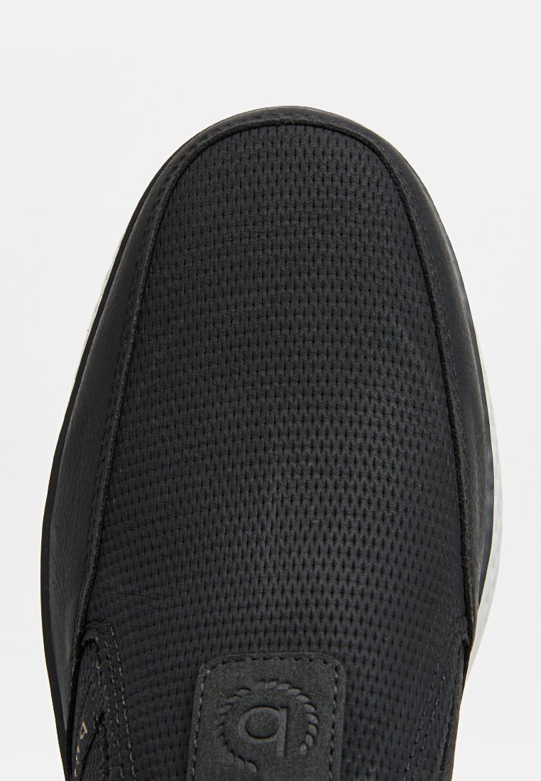 Schwarze Sneaker mit einem strukturierten Mesh-Obermaterial, glatten Lederelementen und einer Gummisohle. Mit Logo-Patch an der Seite.