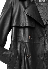 Zwarte leren jas met een dubbelzijdig ontwerp, grote kraag en zijzak. Voorzien van contrasterende knopen en een gestreepte voering.