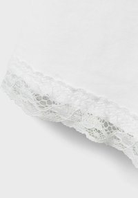 Tela de algodón blanca con un intrincado borde de encaje en el dobladillo, presentando un borde en forma de onda y patrones florales en un estilo delicado.