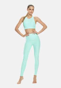 Mentazöld sportmelltartó és magas derekú leggings, rugalmas anyagból készült, varrás nélküli dizájnnal és sima textúrával.