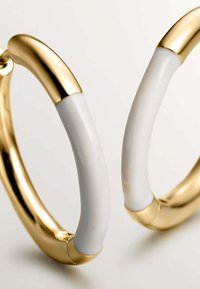 Pendientes de aro de oro con incrustaciones de resina blanca lisa, mostrados en primer plano sobre un fondo claro y sencillo.