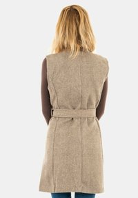Beżowa bezrękawnik wełniany z paskiem w talii, o gładkiej fakturze i dopasowanym kroju, widok z tyłu.