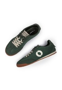 Baskets vert foncé avec des lacets crème, des semelles marron et un logo circulaire blanc sur le côté, montrées vue de dessus et de côté.