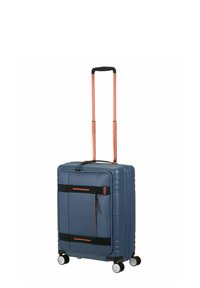 Valise rigide bleue avec double poignée rétractable, accents orange, sangles noires et quatre roues pour la mobilité. Détail de surface texturée.