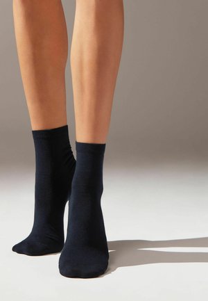 Calcetines tobilleros de color azul marino, confeccionados en una tela suave y elástica, con un puño doblado y un diseño de punta sin costuras.
