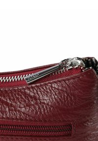 Bolsa de cuero burdeos con una superficie texturizada, herrajes de cremallera plateados y un pequeño bolsillo exterior con cremallera para mayor funcionalidad.