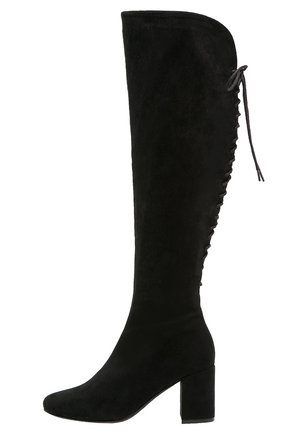 Stivale sopra il ginocchio in suede nero con tacco a blocco, caratterizzato da una parte superiore curva e dettagli con lacci lungo il lato esterno.