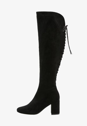 Stivale sopra il ginocchio in suede nero con tacco a blocco, caratterizzato da una parte superiore curva e dettagli con lacci lungo il lato esterno.