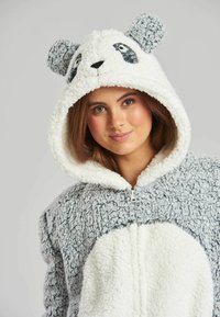 Tutina a tema panda in morbido e soffice tessuto. Colori grigio e bianco con cappuccio dotato di orecchie da panda e dettagli facciali ricamati. Chiusura con zip frontale.