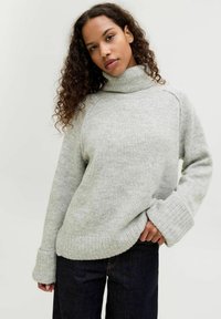 Jasnoszary sweter z golfem, z prążkowanymi mankietami i dołem, wykonany z miękkiego materiału. Stylizowany w luźnym fasonie. W zestawieniu z ciemnymi dżinsami.