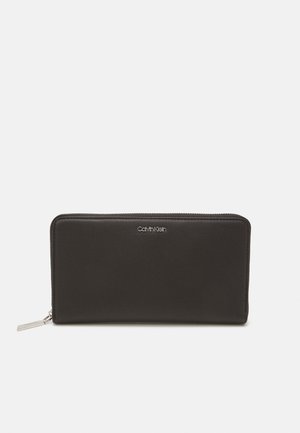 Black leather wallet with a smooth texture, rectangular shape, zip closure, and a silver logo on the front. Compact and minimalist design.