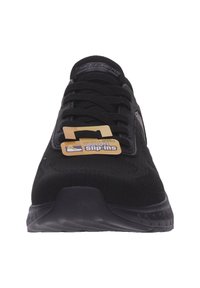 Zapatillas deportivas negras con parte superior de tela texturizada, diseño con cordones y suela de goma. Presenta una etiqueta que indica "entrada sin manos".