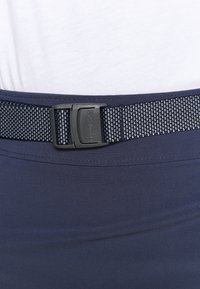 Cinturón azul marino con un diseño texturizado y tejido, con una hebilla de plástico negro. El cinturón está unido a una cintura de tela suave y ajustada.