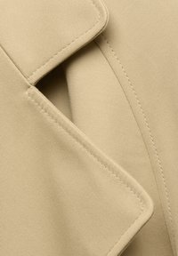 Beezik kangas, sile pind ja märgatav voldi ja õmblustega. Omab krae äärt, millel on täpsed õmblused, et saavutada kohandatud välimus.