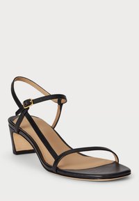 Must must sandaalid beežilt taldalt, millel on madal kaldu rand, õhukesed rihmad ja kuldne sanga detail pahkluuringil.