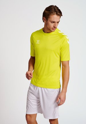 Geel sportshirt van lichtgewicht stof, met korte mouwen en zijkantaccenten, gecombineerd met witte shorts.