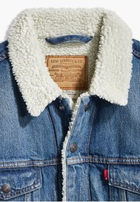 Jeansjacka med en vit sherpa-krage, framknäppning med knappar, två bröstfickor och en hängande etikett med varumärkesinformation.