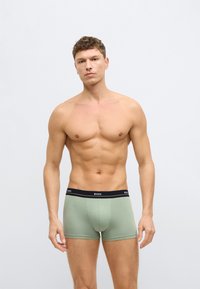 Zielone, bawełniane bokserki z czarną elastyczną talią, na której znajduje się nazwa marki "BOSS". Dopasowany krój zapewnia komfort i wsparcie.