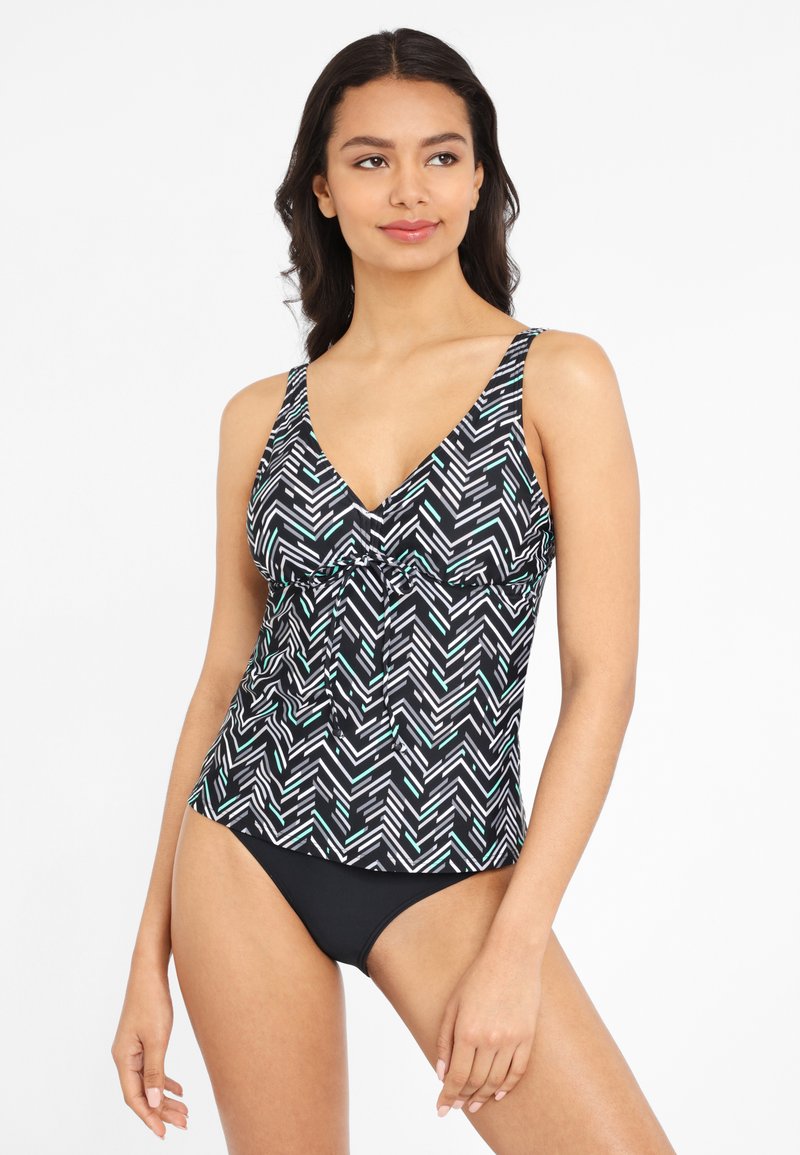 Zwart-witte tankini top met geometrisch patroon, voorzien van een V-hals, verstelbare bandjes en een geplooid detail aan de voorkant. Gecombineerd met zwarte bikinibroekjes.