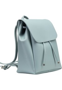 Sac à dos en cuir bleu clair avec un rabat, fermeture à cordon, et accents métalliques carrés. Texture lisse et forme structurée.