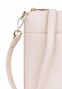 Křížové tělové kožené kabelky s přezkou ve zlaté barvě a jedním nastavitelným popruhem; má hladkou texturu a minimalistický design.